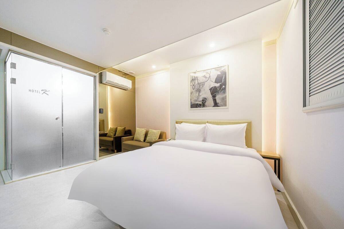 Una camera d'albergo con un letto grande, una poltrona, una scrivania e un armadio.