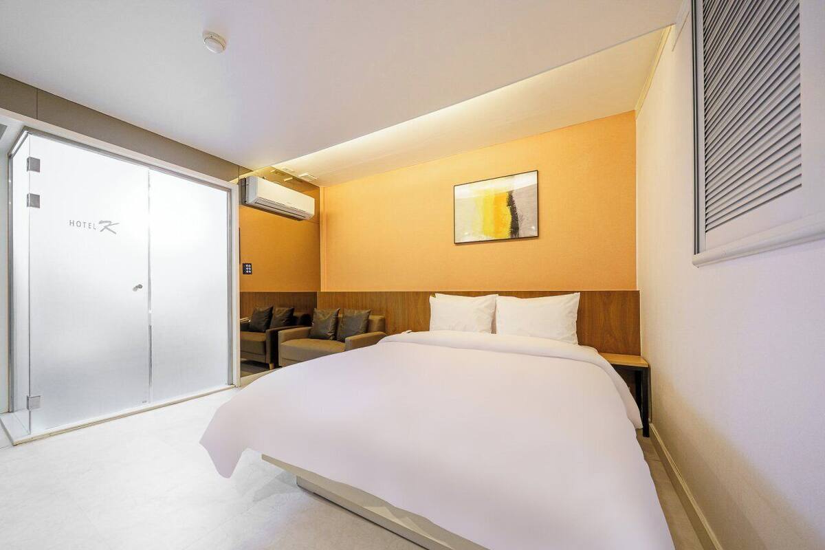 Una moderna camera d'albergo con un letto grande, un divano, una scrivania e una porta scorrevole.