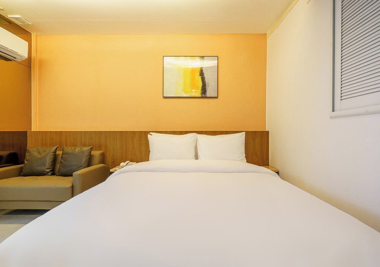 A hotel room with a bed, a sofa, and a painting on the wall.
