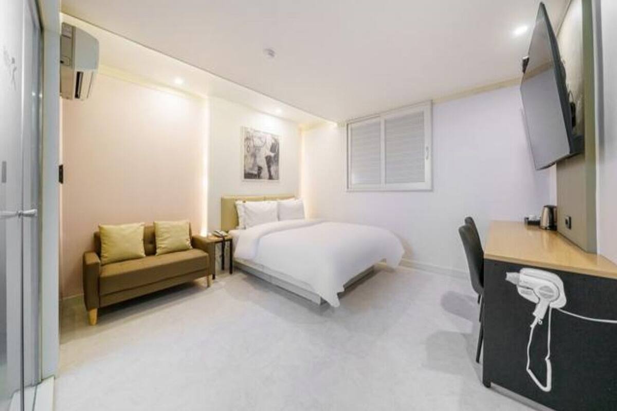 Una camera d'albergo moderna con un letto, una scrivania, una sedia, un divano e una TV.