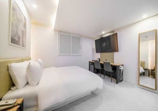 A bedroom with a bed, desk, chair, television, and a large mirror. - Ilsan Hotel K (Goyang)