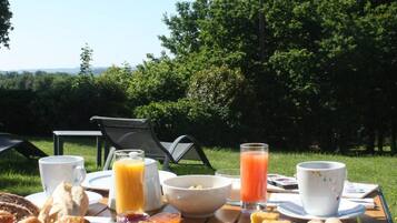 Un buffet de petit-déjeuner avec une variété d’aliments et de boissons, installé sur une table à l’extérieur.