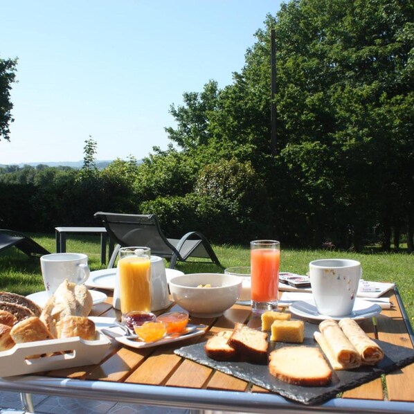 A breakfast setup with a variety of food items and drinks on a table outdoors. - Latitude Ouest Hotel Restaurant Spa (Locronan)