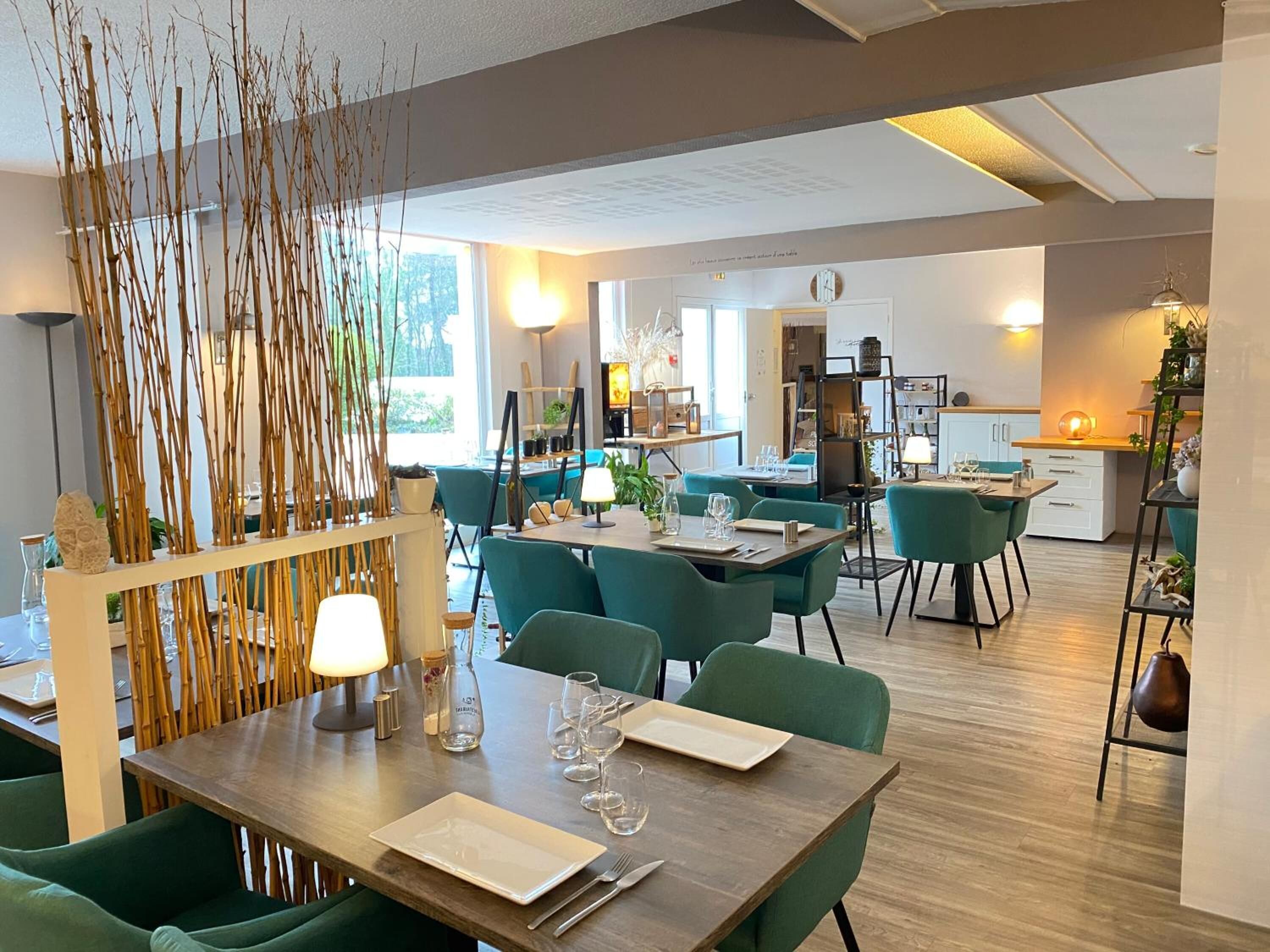 Un espace repas moderne avec des chaises à revêtement vert, une table en bois et un paravent décoratif en bambou.