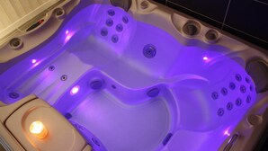 A hot tub with multiple jets, a control panel, and a lit candle. - Latitude Ouest Hotel Restaurant Spa (Locronan)