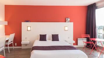 Une chambre d’hôtel avec un grand lit, un bureau, une chaise et une petite table.