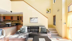 Ein Wohnzimmer mit einer Eckcouch, einem Couchtisch und einer Treppe, die in einen oberen Stock führt.