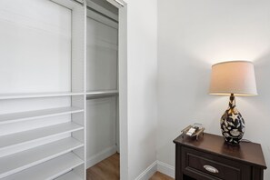 Ein Zimmer mit geschlossenem Schrank, einem Nachttisch mit Lampe und einem Beistelltisch.