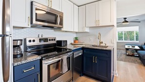 A modern kitchen with stainless steel appliances, white cabinetry, and a granite countertop. - Walk to Downtown Delray and beach.   Huge fenced-in yard for dog (Delray Beach)