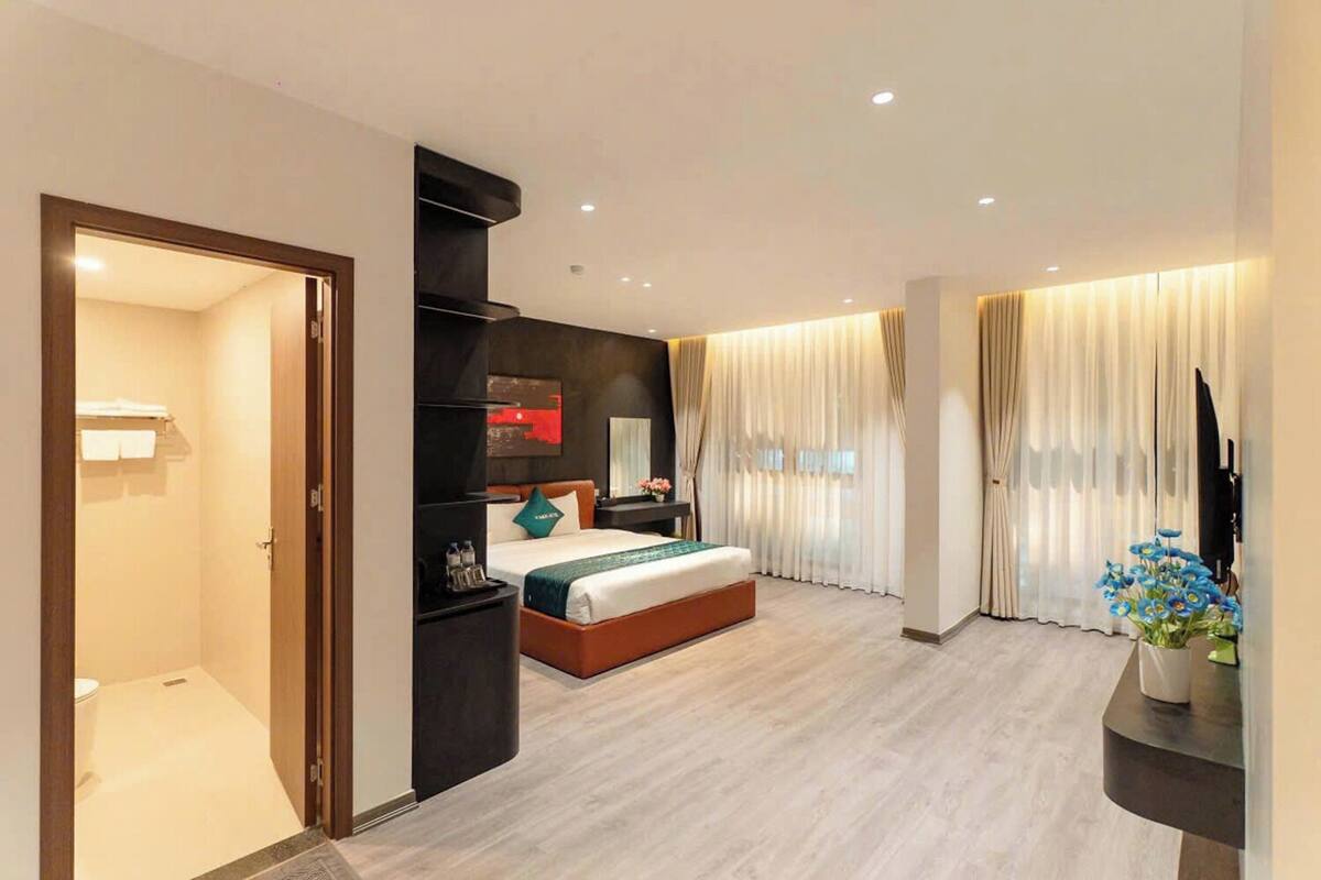 Ein modernes Hotelzimmer mit Bett, Nachttisch und Fernseher.