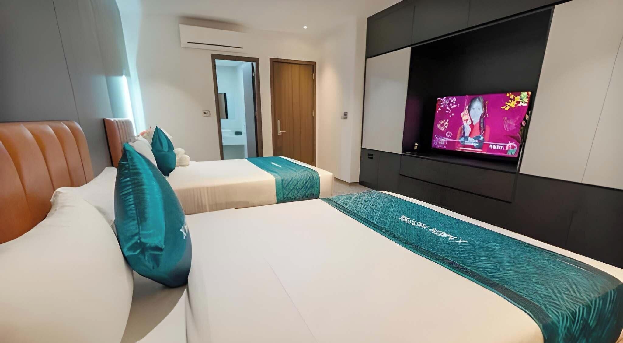 Ein Hotelzimmer mit zwei Betten, einem Fernseher und einer Tür zu einem Badezimmer.