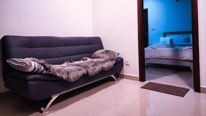 Una stanza con un divano scuro, una coperta in pelliccia e un letto con parete e ventilatore a soffitto blu.