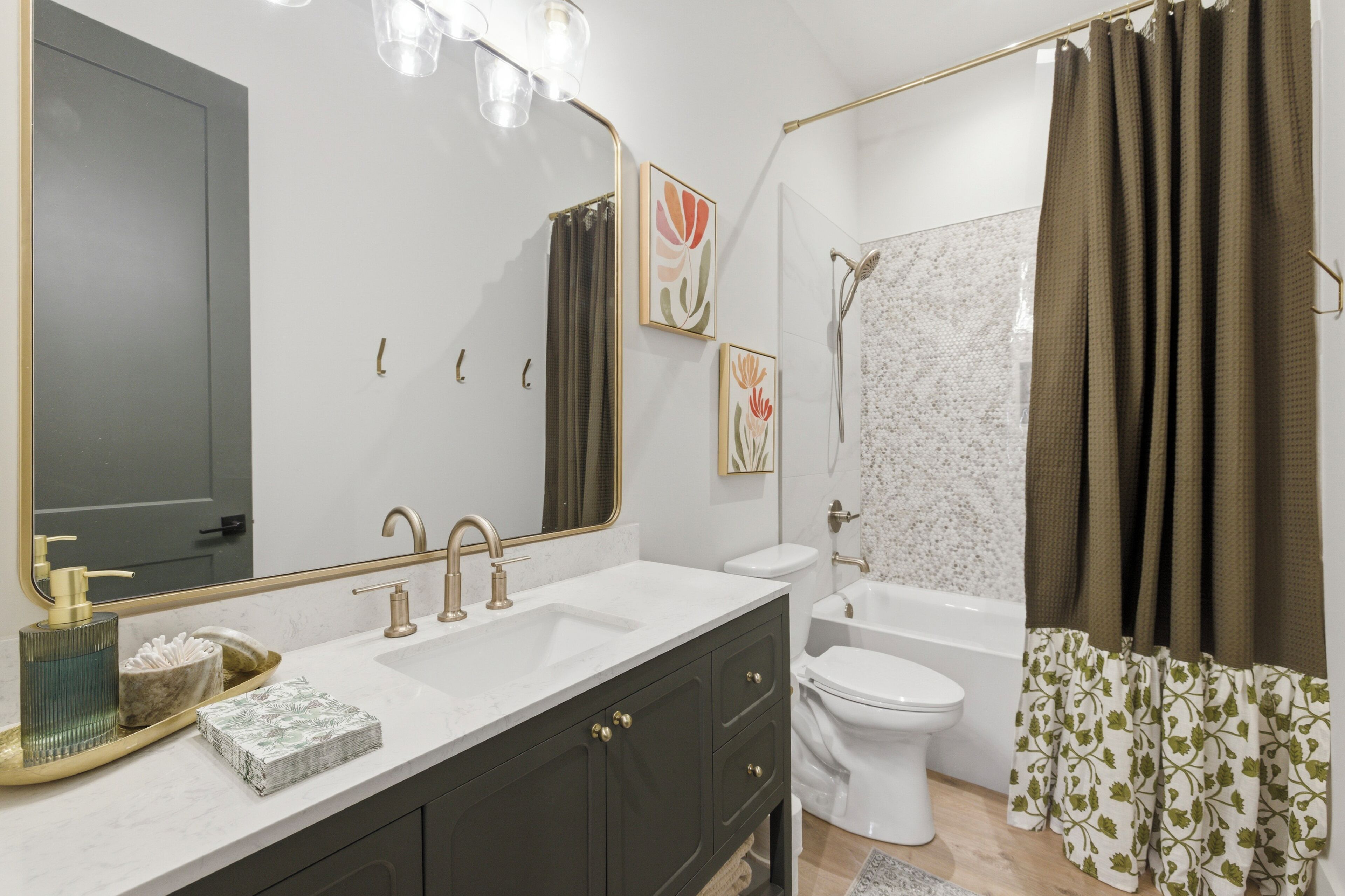 A bathroom with a large mirror, a sink, a toilet, and a bathtub.