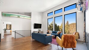 En moderne stue med en blå sofa, en gul lænestol og et fjernsyn på væggen.