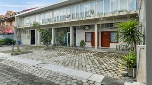 Ein zweistöckiges Gebäude mit Balkon, großen Fenstern und Topfpflanzen.