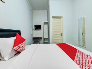 Habitación de hotel con cama, televisor montado en la pared, armario y espejo.