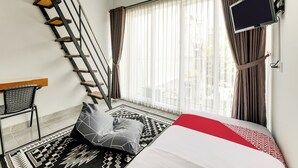 Ein modernes Hotelzimmer mit Bett, Flachbildfernseher, Schreibtisch und einer Treppe.