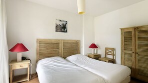 Une chambre à coucher comprenant un lit, deux tables de chevet avec des lampes, une chaise et des armoires en bois.