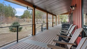 A covered outdoor seating area with wooden benches and a view of a fenced property. - Creek View Vacation Home (Rapid City)