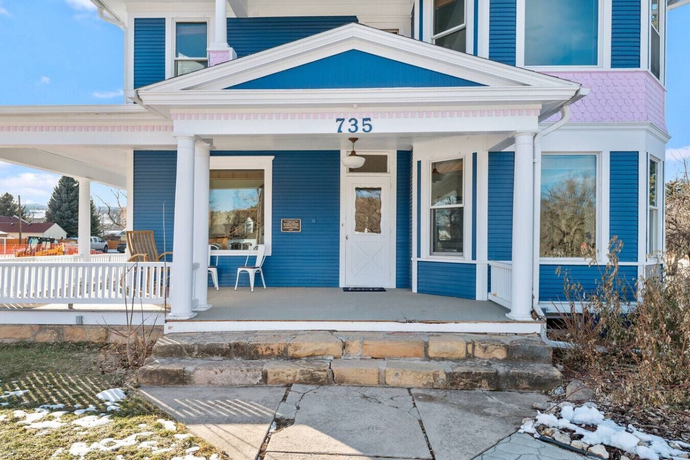 A two-story building with a porch, numbered 735, and a stone foundation.