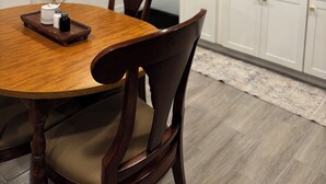 A dining table with chairs, a kitchen area with cabinets, a window, and a mirror on the wall. - Delightful 2-bedroom basement apartment in Potomac. (Potomac)