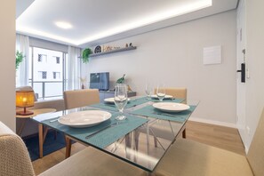 A modern dining area with a glass table, chairs, and a kitchen in the background. - Jabaquara 53 2q 4p (São Paulo)