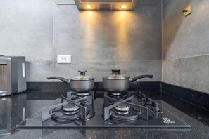 Een moderne keuken met een gasfornuis, twee pannen, een broodrooster en een in de muur gemonteerde oven.