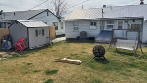 Un cortile sul retro con una casetta degli attrezzi, un’altalena e un trampolino.