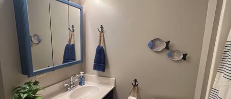 A bathroom with a sink, mirror, toilet, and decorative fish.