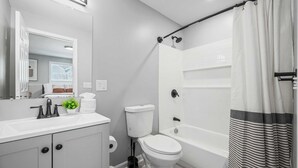 Een badkamer met toilet, wastafel en bad.