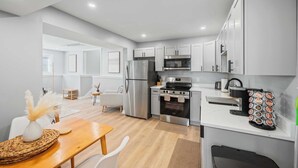 Een moderne keuken met roestvrijstalen apparatuur, een eethoek met een houten tafel, en lichtgekleurde muren.