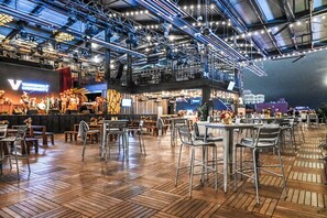 Ein Essbereich mit Tischen und Stühlen, eine Bühne mit Band und eine hohe Decke mit freiliegenden Balken.