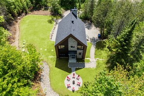 A lodge with a stone exterior, a central fireplace, and a circular seating area. - La Belle Montagne- Luxury Ski & Spa (saint côme)