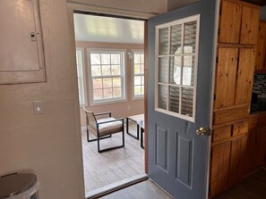 Ein Zimmer mit einer Tür zu einer Terrasse, auf der ein Stuhl und ein Tisch stehen.