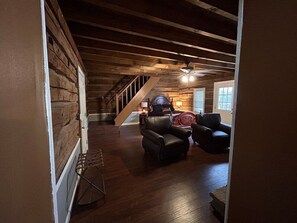 Ein geräumiges Wohnzimmer mit Holzbalkendecke, einer Treppe und einem Kamin.