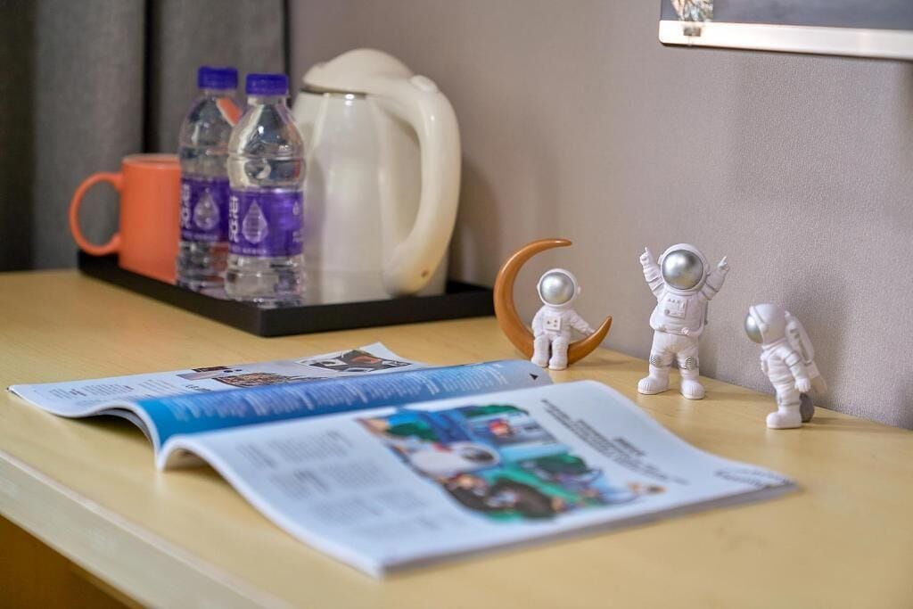 Une table avec un magazine, des bouteilles d’eau, une cafetière et des figurines d’astronautes.