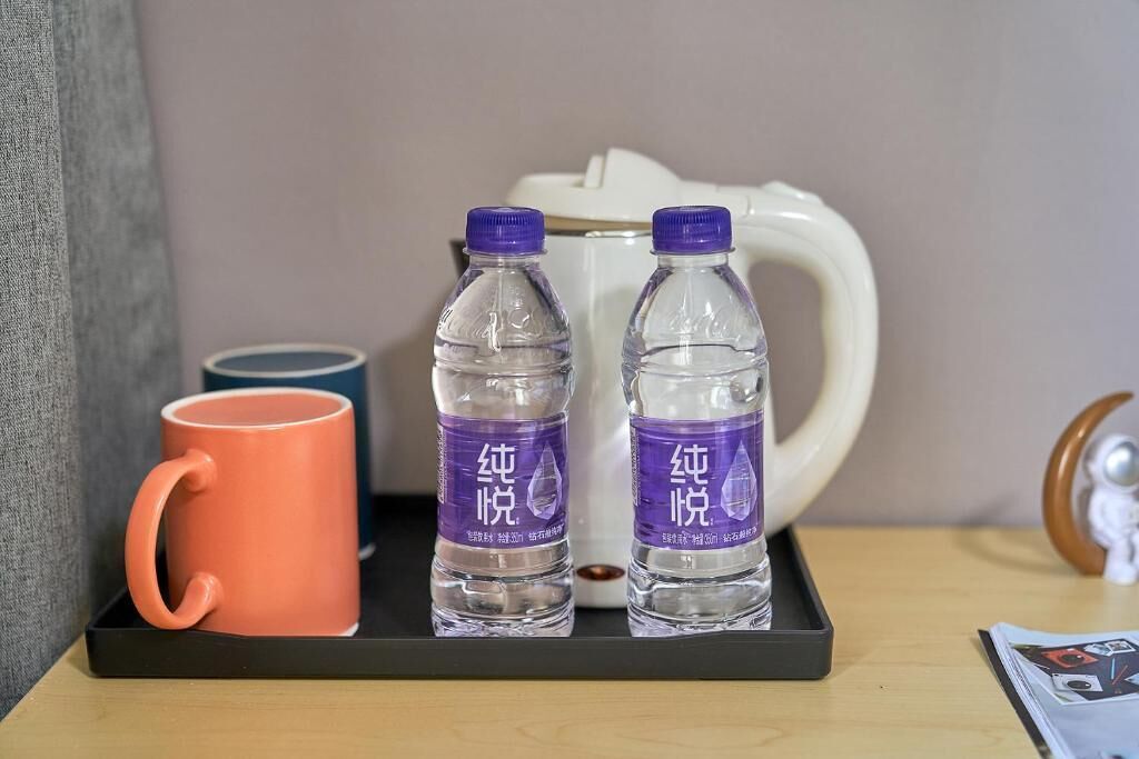 A tray with two water bottles, a mug, and a white pitcher on a table.