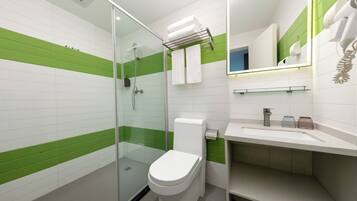A modern bathroom with a glass shower enclosure, a white toilet, and a sink with a mirror above it.