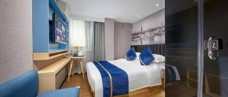 A modern hotel room with a bed, a desk, a chair, a TV, and a glass shower enclosure.