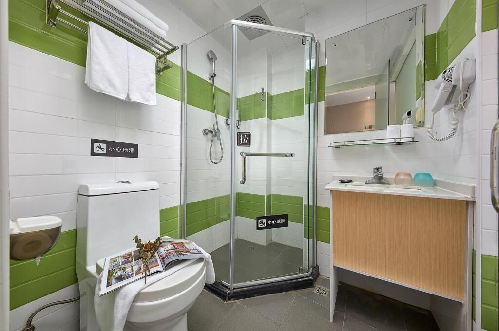 A bathroom with a glass shower enclosure, a toilet, a sink with a mirror, and a towel rack.