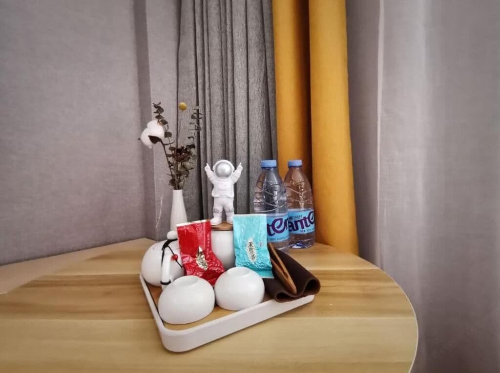 Una bandeja con botellas, una figurita blanca y un bolso rojo sobre una superficie de madera.