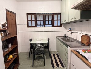 Una cocina compacta con una mesa de comedor, sillas, un ventanal con vidrios esmerilados y un lavamanos.