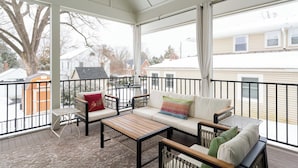 En overdækket balkon med sofa, stole og et bord.