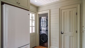 Un cuarto de lavado con un refrigerador blanco, una lavadora y una puerta.