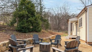 Un patio con sillas Adirondack, una fogata y un muro de piedra.
