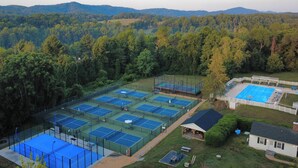 Un complejo de canchas de tenis rodeado de colinas boscosas.