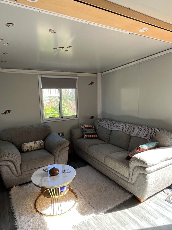 Sala de estar com dois sofás, uma mesa de centro e janela com vista para áreas verdes.