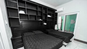 A bedroom with two beds, a wardrobe, and a built-in shelving unit.