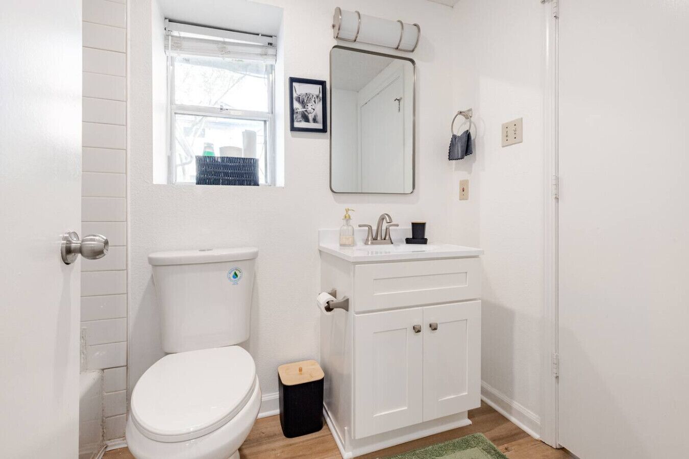 A bathroom with a toilet, sink, mirror, and a small window.