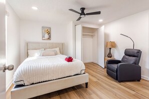 A bedroom with a bed, a chair, a ceiling fan, and a painting. - Renovated Brentwood Home Near DT, Domain & Q2 (Austin)